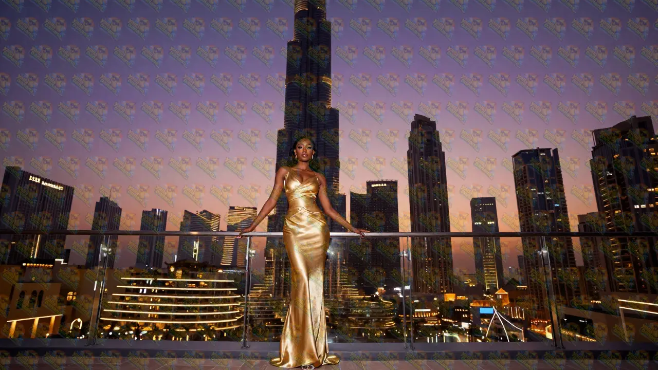 Elegant Black woman in a gold gown on a Dubai rooftop with the Burj Khalifa behind her.