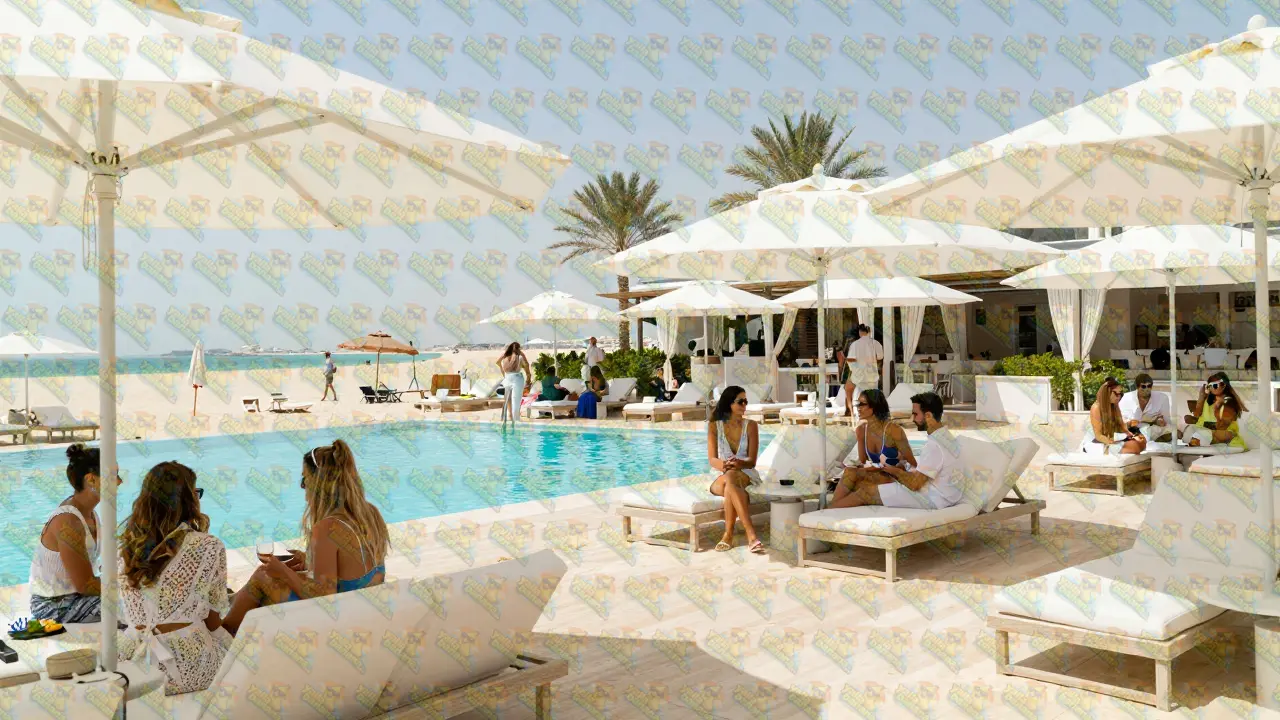 People socializing at a luxury beach club in Dubai with turquoise pools.