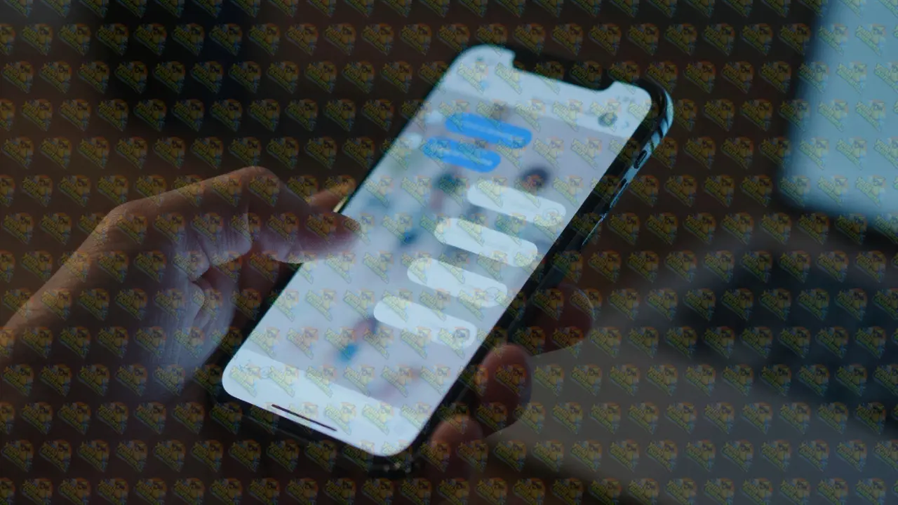 Close-up of a hand using an encrypted messaging app on a smartphone in dim light.